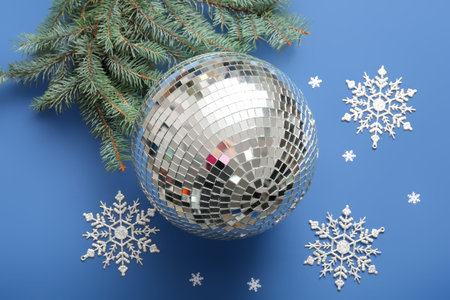 Composition with disco ball, Christmas decor and fir tree branch on blue background, closeup