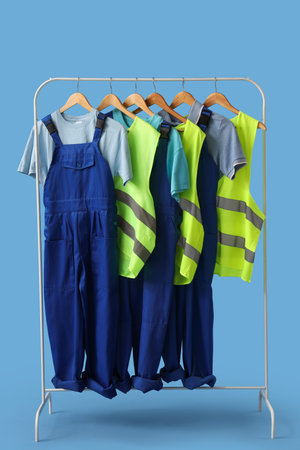 Rack with worker's uniform on blue background