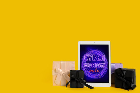 Tablet with gift boxes on yellow background. Cyber Monday Sale