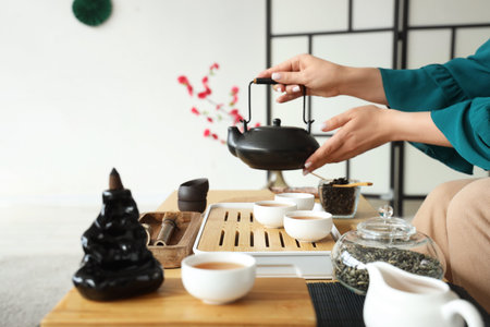 Woman with black tea set on table at home