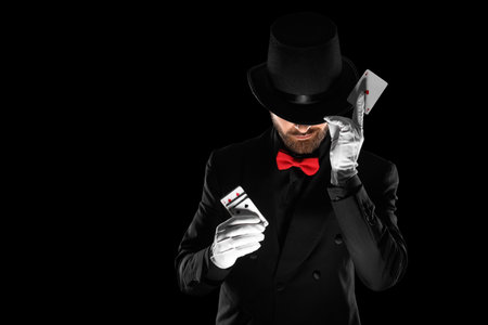 Male magician with playing cards on black background