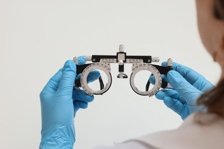 Eye care and vision testing, optometrist holding trial frame for prescription glasses in medical clinic for ophthalmology examination and health checkup