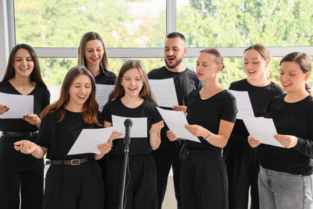 Choir performance and team collaboration, diverse group of singers practicing music with sheet music and microphone in a bright rehearsal studio