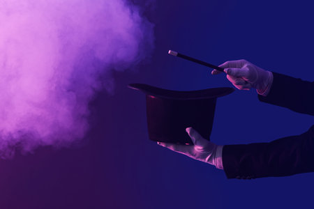 Male magician's hands with hat and wand on dark background