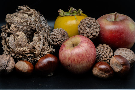A composition of typically autumnal fruits such as chestnuts, walnuts, persimmons or the Campanian Annurca apple, enhancing their beauty and detail.の写真素材
