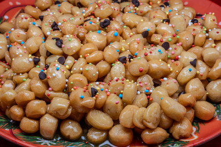 Struffoli are a typical dessert of the Neapolitan Christmas tradition, made up of small balls of sweet dough, fried and then covered in honey and colorful decorations.の写真素材