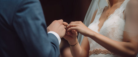 Wedding hands of the bride and groom ceremonially put wedding rings on their fingers. Header banner mockup with copy space. AI generated.の素材