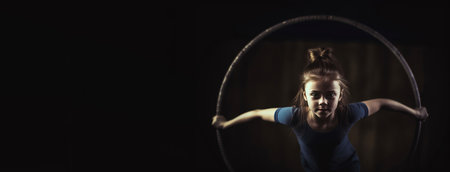 Girl child in a gymnast costume doing a sports exercise in the gym, black background isolate. Header banner mockup with copy space.の素材