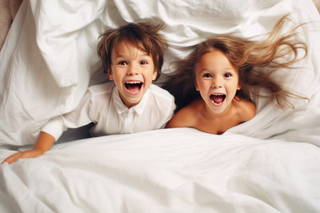 Cheerful children, sisters, brothers play and jump on the bed in the bedroom. Family happiness, traditional values.の素材