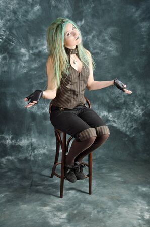 Pretty young blonde girl with green hair in the steampunk style demonstrates that she was not succeeded in somethingの写真素材