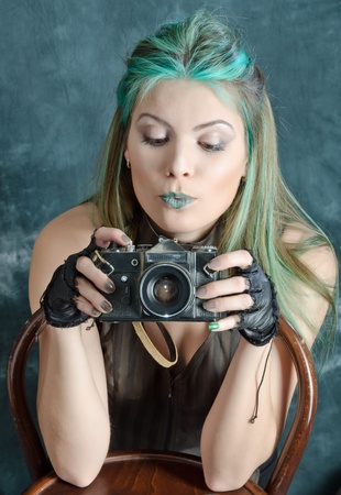 Photo session of the pretty young blonde girl with green hair in the steampunk style with photo cameraの写真素材