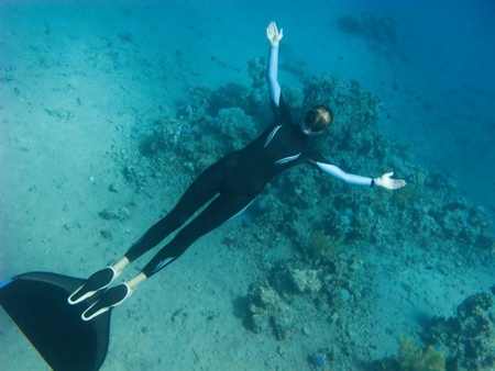 Beautiful freediver girl poses near the coral reef and sand bottom of the Red Seaの写真素材