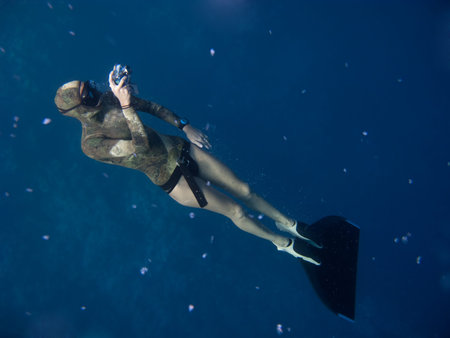 Freediver with monofin takes photo while standing under the surface