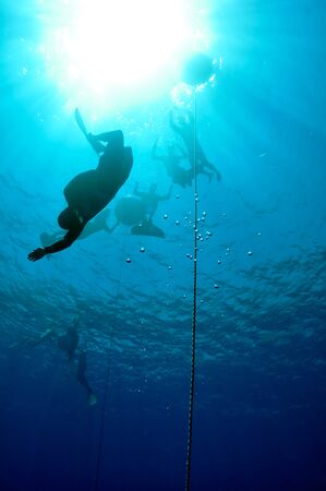 One freediver started his dive down to the depth, while others are waiting for him on the surfaceの写真素材