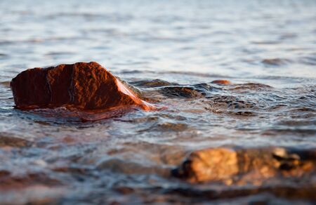 Small stones and rocks at the edge of the sea and in the wavesの写真素材