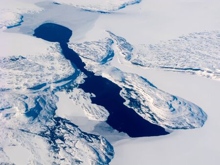 Aerial view of the Canadian lake, surrounded by rocks and snowの写真素材
