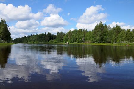 The beautiful picture of Karelian forest at the edge of a lake, and some huge boulder in this lakeの写真素材