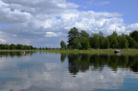 The beautiful picture of Karelian forest at the edge of a lake, and some huge boulder in this lakeの写真素材