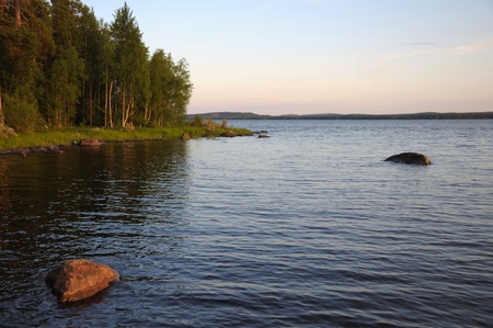 The beautiful picture of Karelian forest at the edge of a lake, and some huge boulder in this lakeの写真素材