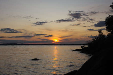 The final stage of a cloudy sunset above the huge lake in Karelia region. The picture is colorful and relaxing.の写真素材