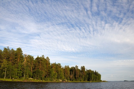 The beautiful picture of Karelian forest at the edge of a lake, and some huge boulder in this lakeの写真素材