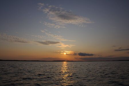 The final stage of a cloudy sunset above the huge lake in Karelia region. The picture is colorful and relaxing.の写真素材