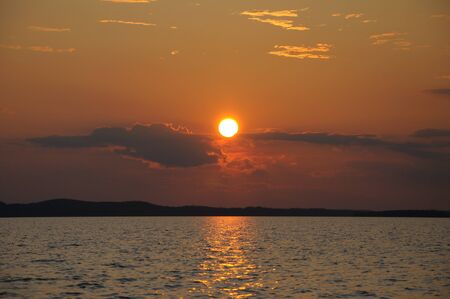 The final stage of a cloudy sunset above the huge lake in Karelia region. The picture is colorful and relaxing.の写真素材
