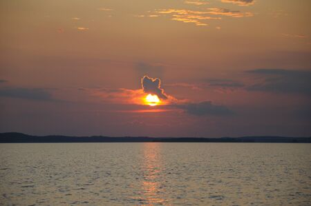 The final stage of a cloudy sunset above the huge lake in Karelia region. The picture is colorful and relaxing.の写真素材