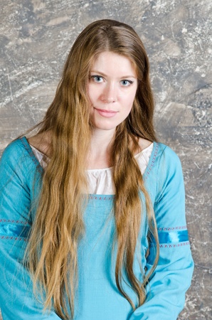 Pretty young woman in historical medieval blue dress poses in studioの写真素材