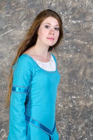 Pretty young woman in historical medieval blue dress poses in studioの写真素材