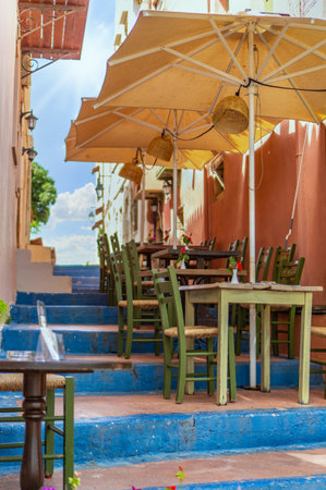 Cozy outdoor cafe on the steps of the stairs in Rethymno, Crete, Greece. Old stone houses, a...