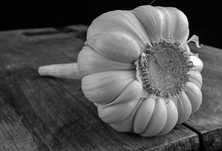 Close up of garlic on a kitchen board. Small depth of sharpness. Emphasis in the foreground. Indoors. Horizontal format. Monochrome.の写真素材
