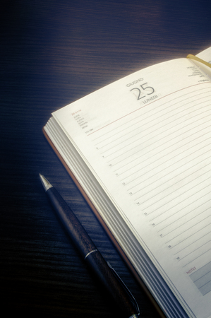 Open notebook and pen nearby. Low contrast. Toning by blue. Vintage. Indoors. Vertical format. Blackout at the edges. Color. Photo.の写真素材