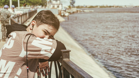 Portrait of a dark-haired teenage boy on the city embankment. Model age 13-14 years. Outdoors. Horizontal format. Vintage. Color. Photo.の写真素材