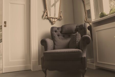 An old vintage armchair stands in the corner of the roomの写真素材