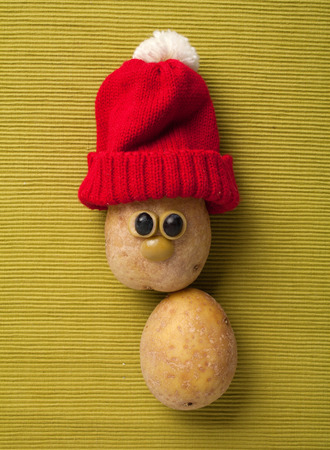 Happy Christmas potato in santa hat on yellow backgroundの写真素材