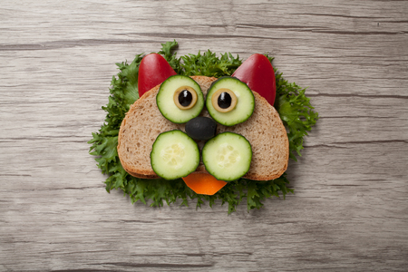 Confused cat made of bread and vegetables on boardの写真素材