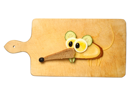 Mouse made with bread, cheese, egg and cucumber on cutting boardの写真素材