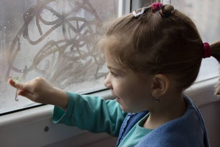 little girl draws a finger on the misted glassの写真素材