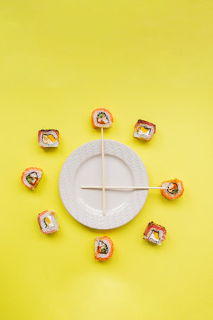 Sushi rolls on a white plate on a yellow background, top viewの写真素材