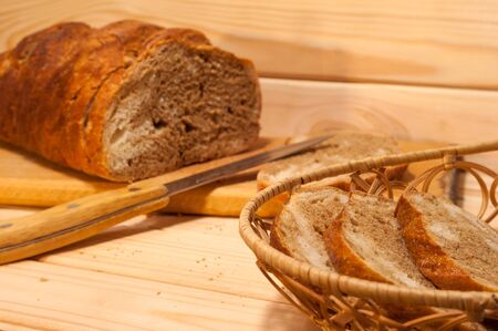marble sliced ??wheat - rye bread on a wooden board with a straw basket and slices of bread in itの写真素材