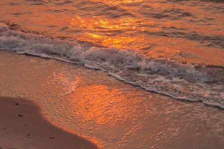 Sea and sand with reflection of the sunsetの写真素材
