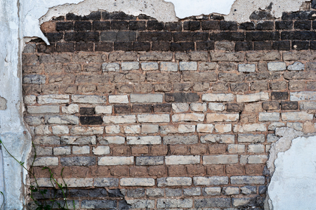 old bare wall with dirty cracked white brickwork and remnants of white plasterの写真素材