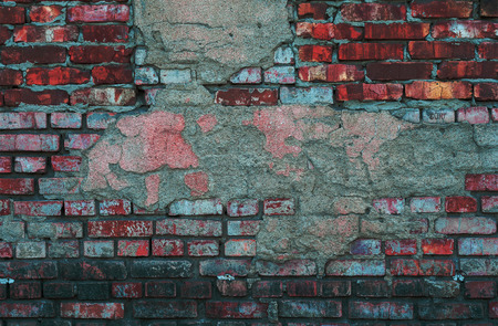 brick wall of old, red, rough brick with shabby white plasterの写真素材
