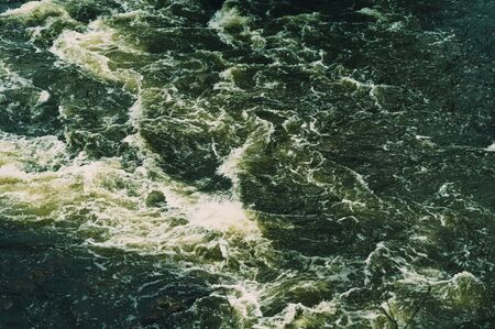 Background, top view, fast flowing river with dark green water and white foam wavesの写真素材