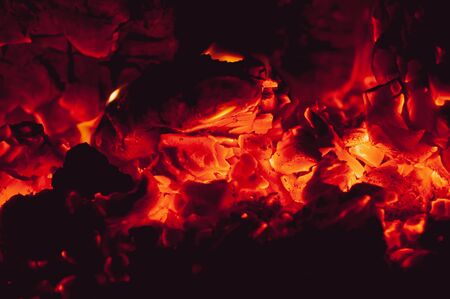 Orange-red bright colorful embers dying bonfire. Tree branches dying in fire. Burning fire on black background close-up. Horizontal background.の写真素材