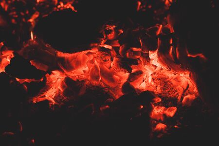 Bright colorful glowing orange-red embers bonfire. Burning fire on black background close-up. Horizontal background.の写真素材
