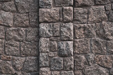 Old darkened from time to time wall with rough granite stonesの写真素材