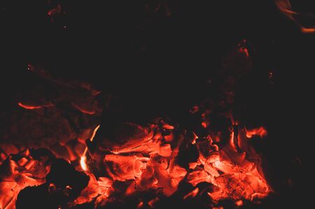 Orange red bright colorful embers dying bonfire. Burning fire on black background close-up. Horizontal background. Tree branches dying in fire.の写真素材