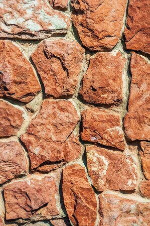 background from the old darkened wall with granite brown roughly processed stones close-upの写真素材